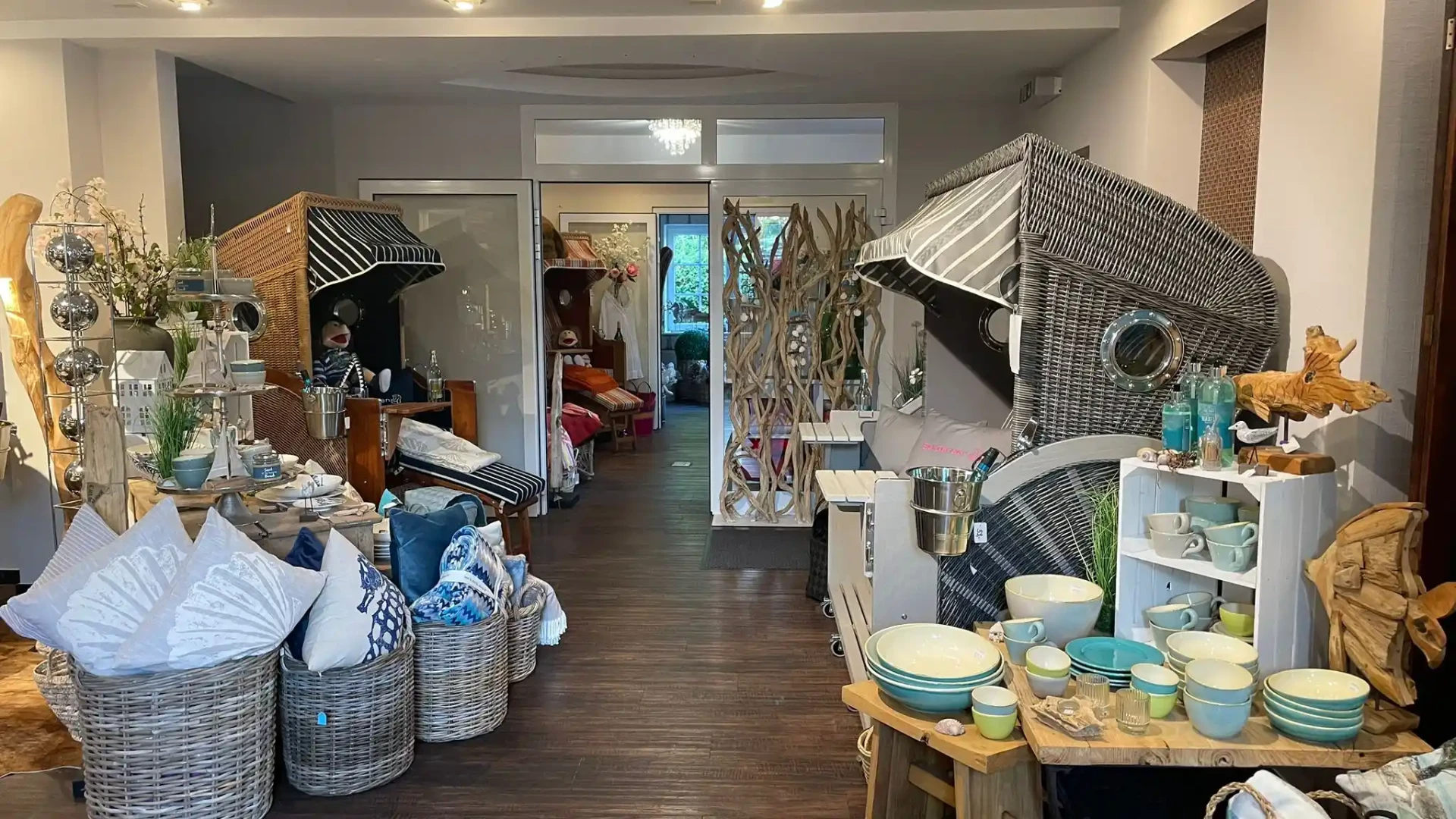 Blick durch den Sea & Ocean Showroom in Hemmelsdorf mit Strandkörben, Geschirr und Kissenkörben